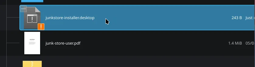 The Downloads folder in Dolphin with junkstore-installer.desktop selected at the top, listed at 243 bytes